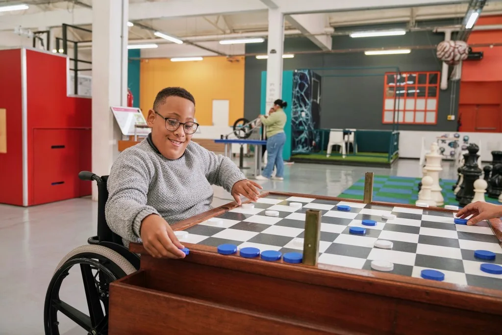 Disabled man in wheelchair at centre playing game with friend
