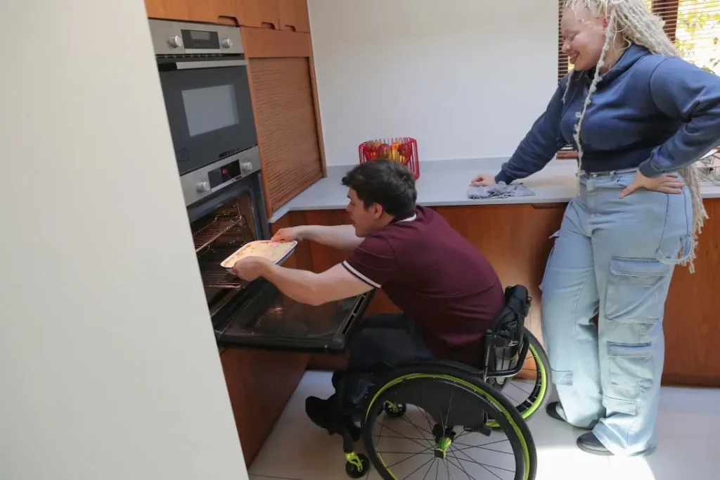 Disabled man in wheelchair baking lasagne with friend