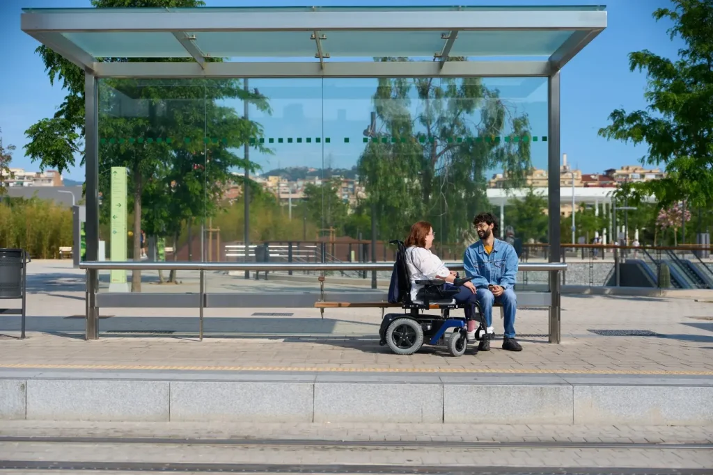 Disabled woman in wheelchair with friend at tram stop